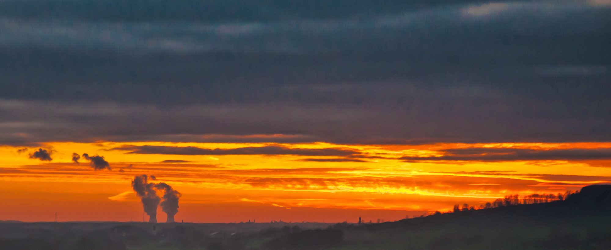 Foto: Sonnenuntergang mit zwei AKW-Kühltürmen im Hintergrund.