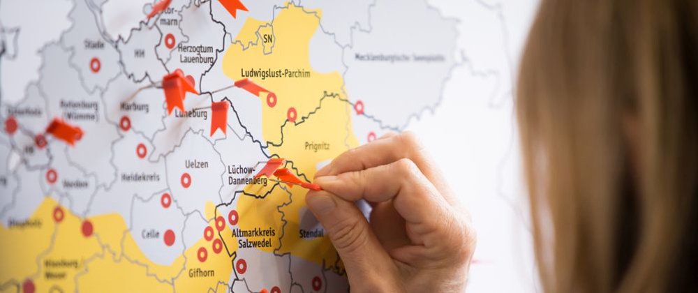 Foto: eine Hand setzt einen Pin in eine Landkarte von Deutschland