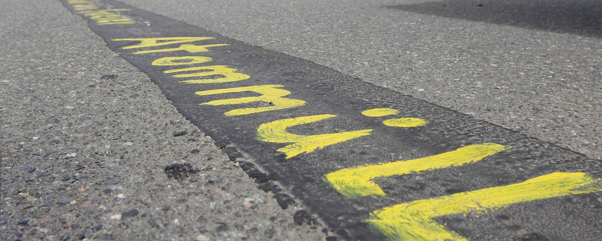 Foto: Das Wort Atommüll steht in gemalten gelben Buchstaben auf Asphalt